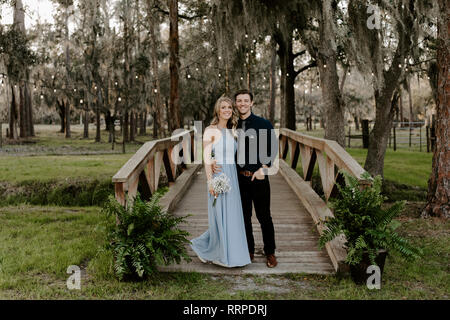 Beautiful Bridesmaid Woman in Blue Dress and Bouquet with Her Date at a Formal Wedding Party Celebration Event Outside in the Woods Taking Couple Port Stock Photo