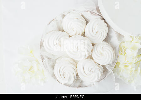 White tender marshmallow in a white box on a light background decoration flowers. Horizontal frame. View from above. Stock Photo