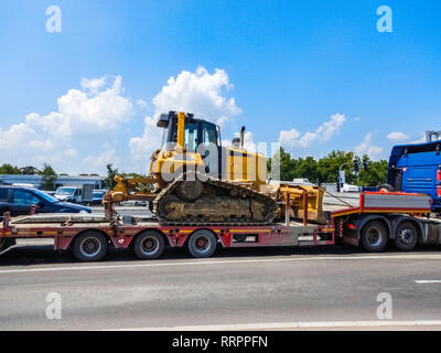 Yellow heavy duty crawler bulldozer on truck trailer in traffic - Transporting bulldozer excavator in everyday street traffic - Tractor bulldozer with Stock Photo