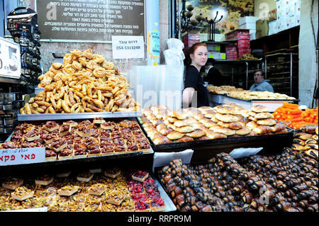 A young female vendor portrayed behind her stall selling traditional Kosher treats at Yehuda Market, Jerusalem, Israel Stock Photo