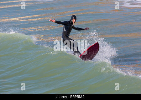 Bournemouth, Dorset, UK. 26th Feb, 2019. UK weather: warm weather continues with another lovely warm sunny day at Bournemouth as visitors enjoy the sunshine at the seaside,  expected to be the hottest day of the year and hottest February day ever. Bournemouth beach is voted the best beach in the UK. Surfer rides the waves. Credit: Carolyn Jenkins/Alamy Live News Stock Photo