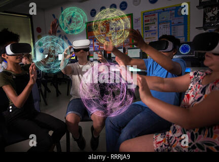 Junior high school students using virtual reality simulators in dark classroom Stock Photo