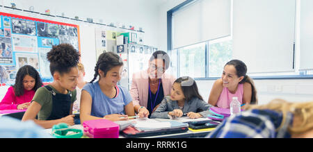 Female teacher and junior high school girl students at desk in classroom Stock Photo