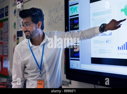 Male teacher leading lesson at touch screen in classroom Stock Photo ...