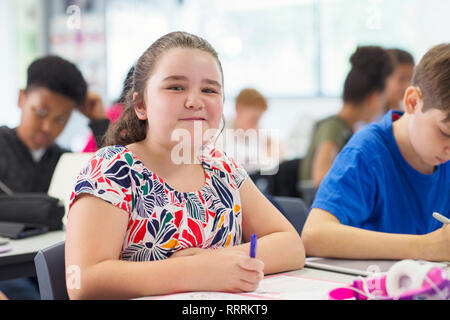 Portrait smiling, confident junior high school girl studying in classroom Stock Photo