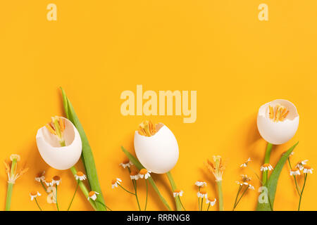 Bright yellow background with spring Easter flowers made of eggshell, creative composition Stock Photo