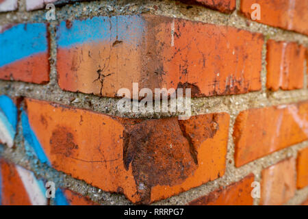 Corner of an old red brick wall with blue graffiti, viewed in close-up Stock Photo