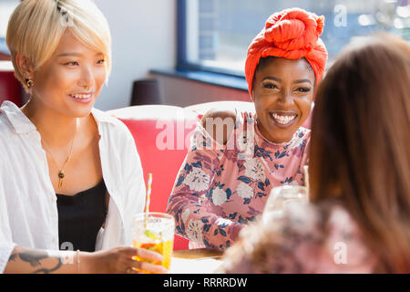 Happy young women friends drinking cocktails, talking in restaurant Stock Photo