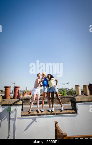 Young women friends taking selfie with camera phone on sunny rooftop Stock Photo