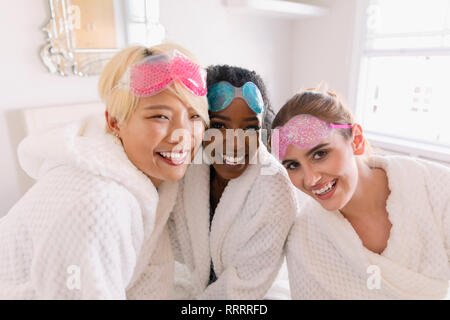 Portrait happy young women friends in bathrobes and eye masks Stock Photo