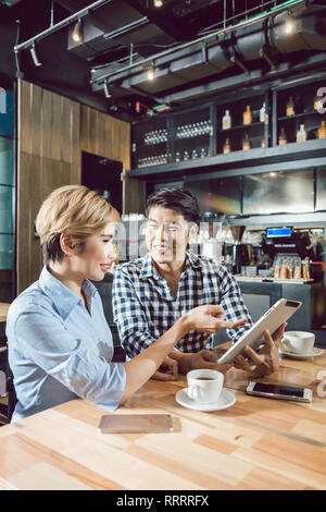 Woman looking at the digital tablet in her boyfriend's hands Stock Photo