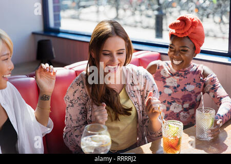 Happy, excited young women drinking cocktails in restaurant Stock Photo