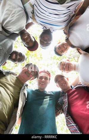 View from below mens group standing in huddle Stock Photo