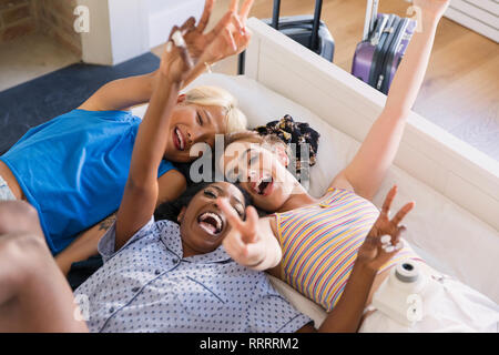 Portrait playful young women friends laying on bed Stock Photo