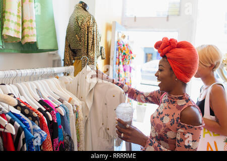 Young woman with smoothie shopping in clothing store Stock Photo