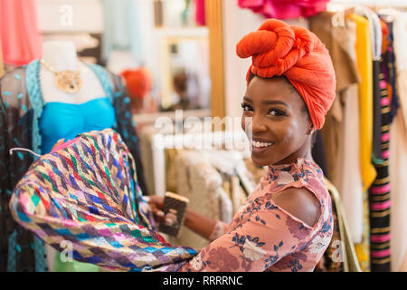 Portrait smiling, confident young woman in headscarf shopping in clothing store