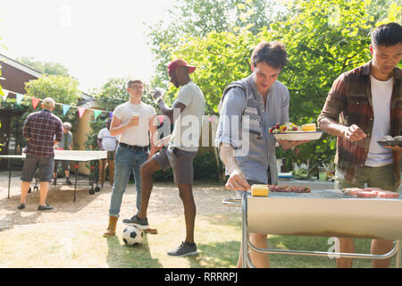 Male friends enjoying barbecue in sunny summer backyard Stock Photo