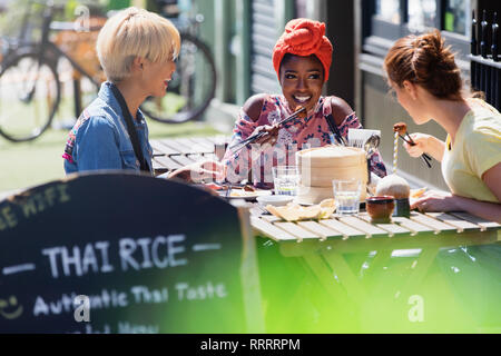 Young women friends enjoying dim sum lunch at sunny sidewalk cafe Stock Photo