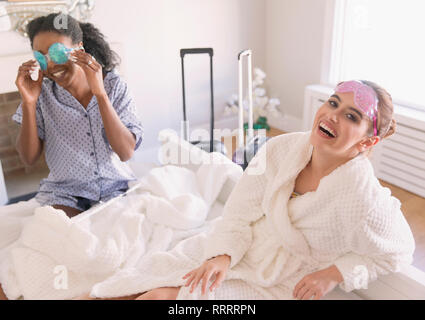 Portrait happy young women friends wearing eye masks in bedroom Stock Photo