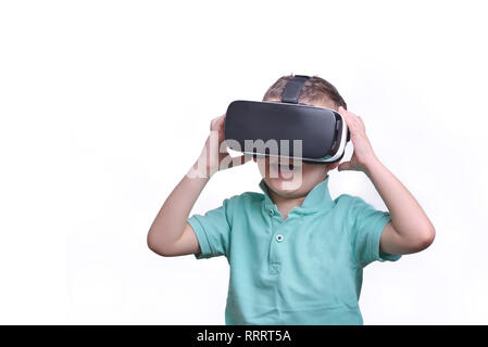 Amazed teen boy wearing virtual reality goggles watching movies or playing video games, isolated on white. Surprised teenager looking in VR glasses. E Stock Photo