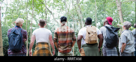 Mens group hiking, standing in a row and bird watching in woods Stock Photo
