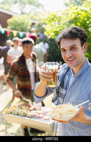 Portrait happy man drinking beer and barbecuing in backyard Stock Photo