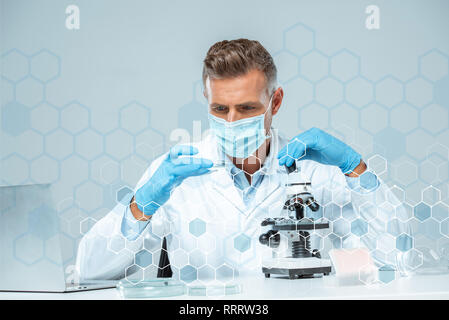 handsome scientist in medical mask and medical gloves making experiment Stock Photo