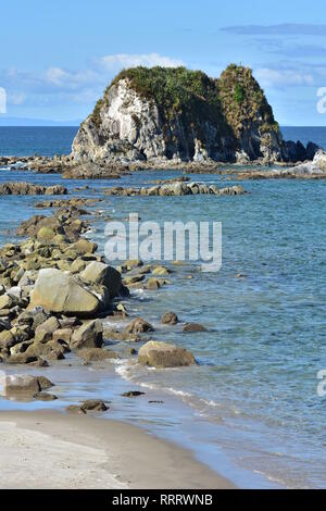 Vertical view of rocks stretching from shore to rocky islet near harbor mouth in Mangawhai Heads. Stock Photo