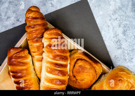 Appetizing delicious ruddy glazed baked buns, pies and pastries with cinnamon and various fillings, made from premium organic flour, laid out on a woo Stock Photo