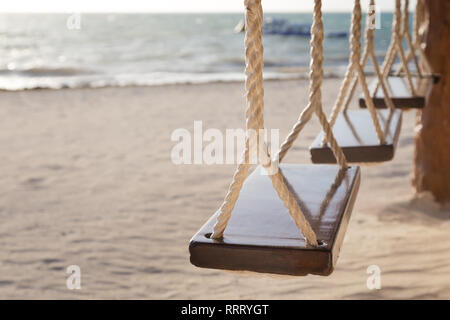 Hanging wooden swing seats at a bar on the beach. Stock Photo