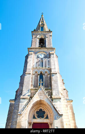 Architectural details of a small church in a French town Neuvy-en-Mauges, France. Warm spring day, vibrant blue sky. Shot from the ground Stock Photo