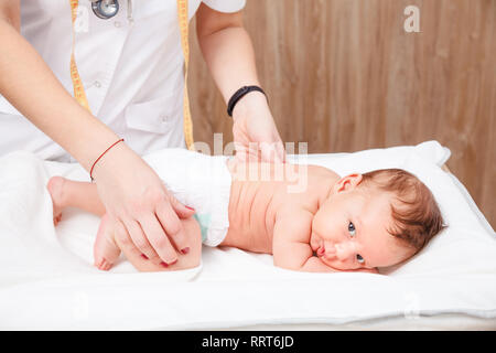 Female pediatrician checking two months baby boy hips during routine medical examination or check-up in pediatric clinic Stock Photo