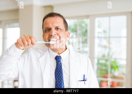 Middle age dentist man holding toothbrush and smiling Stock Photo