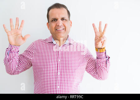 Middle age man wearing business shirt over white wall showing and pointing up with fingers number eight while smiling confident and happy. Stock Photo