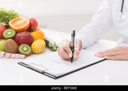 Female nutritionist doctor writing vegetable diet plan Stock Photo