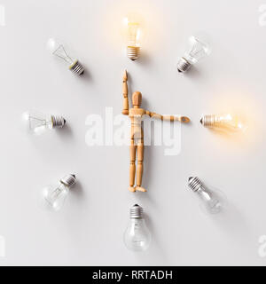 Wooden mannequin carrying glowing light bulbs on white Stock Photo
