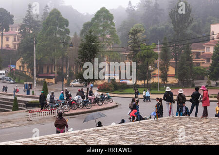 Street scene with locals and tourists walking around the town of Sa Pa on an overcast foggy day, Vietnam Stock Photo