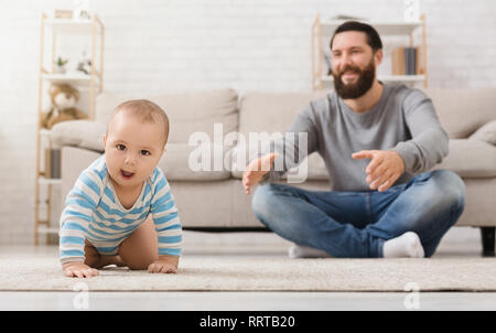 Adorable baby boy crawling on floor with dad Stock Photo