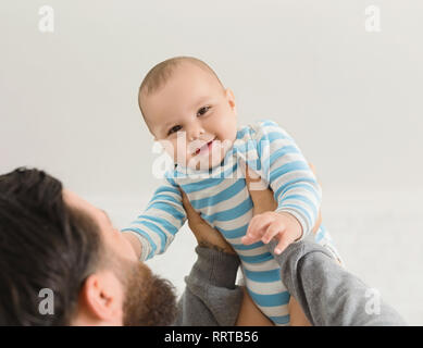 Dad holding happy baby son up in the air Stock Photo