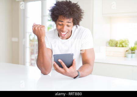African American man using touchpad table screaming proud and celebrating victory and success very excited, cheering emotion Stock Photo