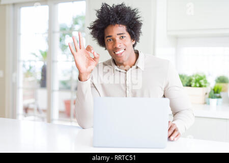 African American man working using laptop doing ok sign with fingers, excellent symbol Stock Photo