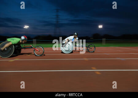 Paraplegic athletes speeding along sports track in wheelchair race Stock Photo