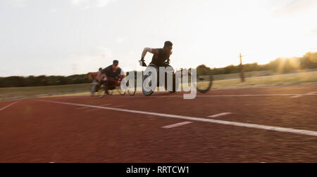 Paraplegic athletes speeding along sports track during wheelchair race Stock Photo