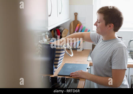 Young woman unpacking groceries in apartment kitchen Stock Photo