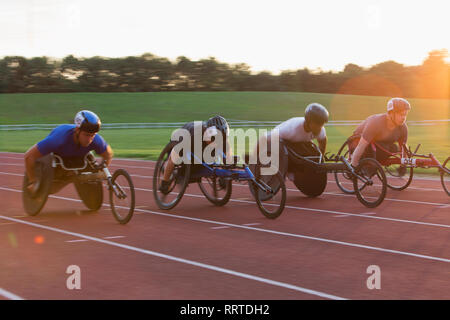 Paraplegic athletes speeding along sports track in wheelchair race Stock Photo