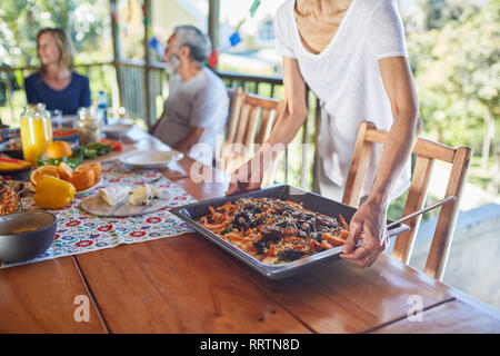 Woman placing food on table in hut Stock Photo