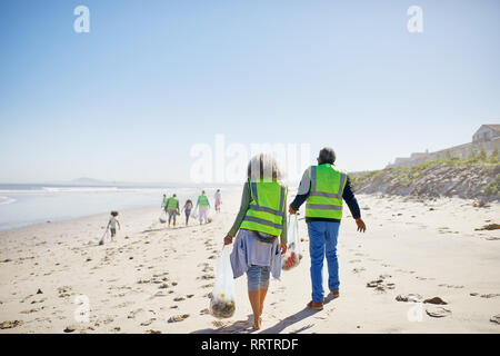 Volunteers cleaning up litter on sunny, sandy beach Stock Photo