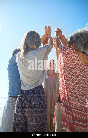 Group standing in circle with arms raised during yoga retreat Stock Photo