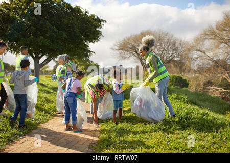 Volunteers cleaning up litter in sunny park Stock Photo