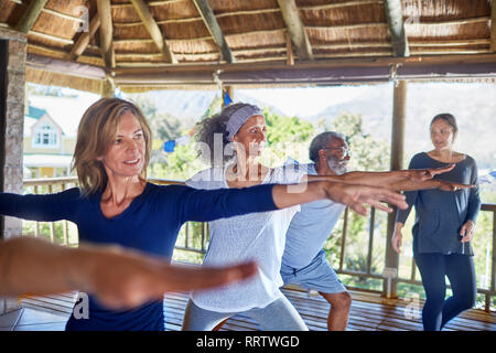 Yoga class practicing warrior 2 pose in hut during yoga retreat Stock Photo